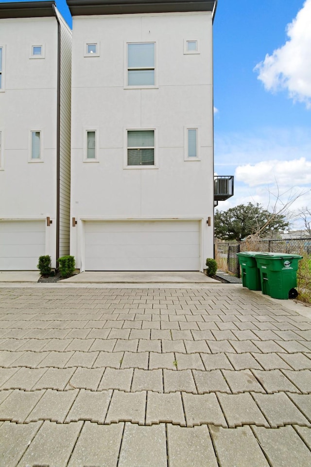 703 Schwartz St, Houston, TX 77020 - view of side of home featuring an attached garage, decorative driveway, and stucco siding