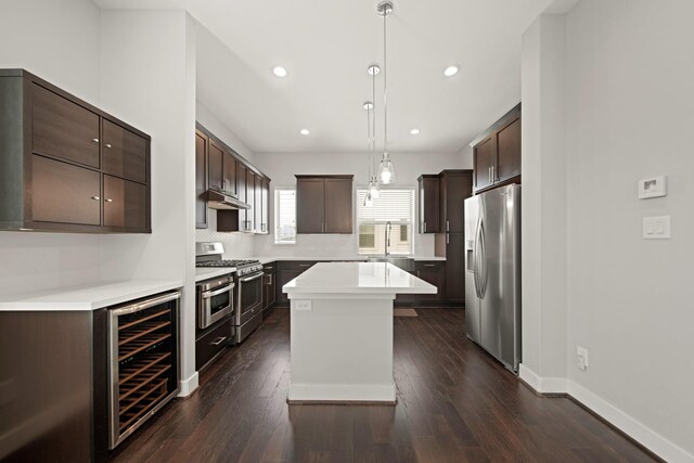 703 Schwartz St, Houston, TX 77020 - kitchen featuring stainless steel appliances, beverage cooler, dark brown cabinetry, under cabinet range hood, and a kitchen island