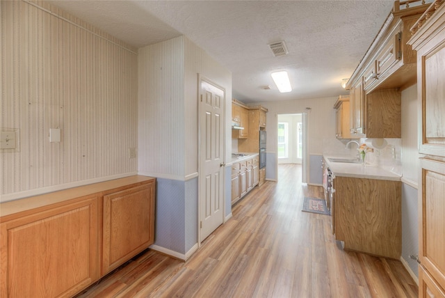 440 Lakeview Drive Loop, Coldspring, TX 77331 - kitchen with light wood finished floors, light countertops, a textured ceiling, under cabinet range hood, and white gas cooktop