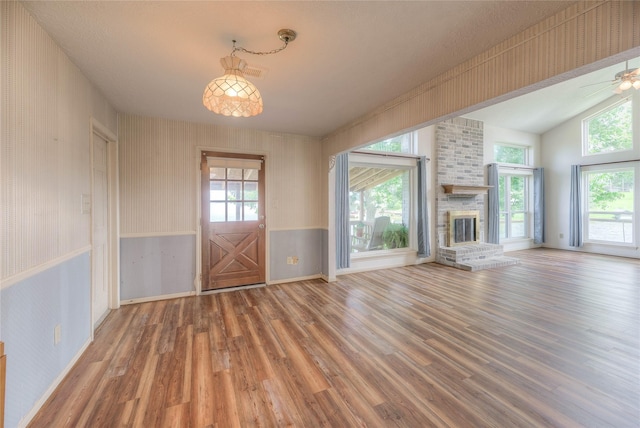 440 Lakeview Drive Loop, Coldspring, TX 77331 - unfurnished living room featuring wood finished floors, vaulted ceiling, a fireplace, a wainscoted wall, and a ceiling fan