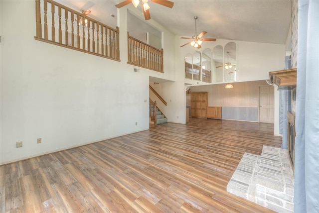 440 Lakeview Drive Loop, Coldspring, TX 77331 - unfurnished living room featuring a ceiling fan, stairs, wood finished floors, a fireplace, and high vaulted ceiling