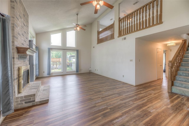 440 Lakeview Drive Loop, Coldspring, TX 77331 - unfurnished living room featuring a ceiling fan, a fireplace, wood finished floors, high vaulted ceiling, and stairs