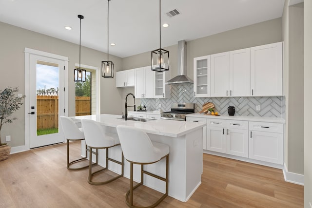 5935 Cebra, Houston, TX 77091 - kitchen featuring stainless steel stove, wall chimney exhaust hood, tasteful backsplash, light wood-style flooring, and recessed lighting