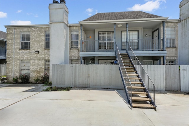 6606 De Moss Dr Unit 1406, Houston, TX 77074 - back of house with stairway, a chimney, brick siding, a porch, and roof with shingles