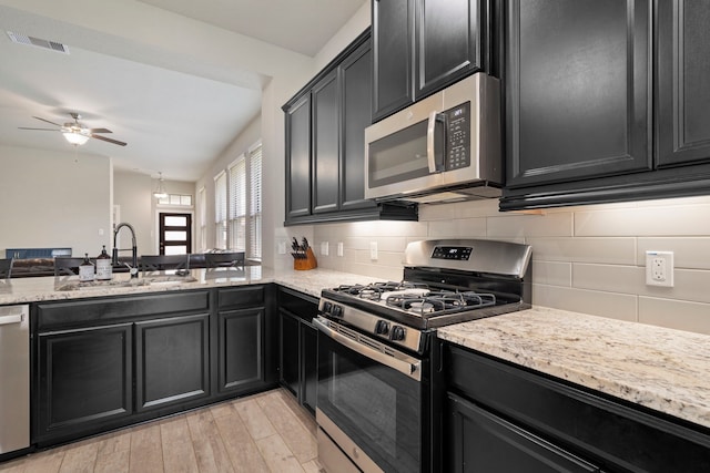 31230 Pinebrook Falls Ln SE, Hockley, TX 77447 - kitchen with stainless steel appliances, dark cabinets, and light wood-type flooring