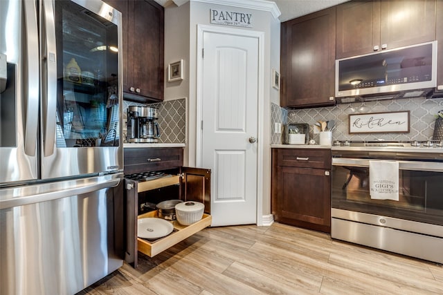 11823 Solon Springs Dr, Tomball, TX 77375 - kitchen featuring appliances with stainless steel finishes, dark brown cabinetry, backsplash, light countertops, and crown molding