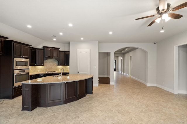 23411 Reynolds Pond Dr, New Caney, TX 77357 - kitchen with appliances with stainless steel finishes, arched walkways, tasteful backsplash, a kitchen island with sink, and a ceiling fan