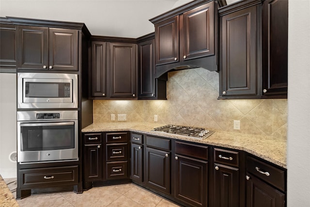 23411 Reynolds Pond Dr, New Caney, TX 77357 - kitchen with appliances with stainless steel finishes, backsplash, light stone countertops, dark brown cabinets, and light tile patterned floors