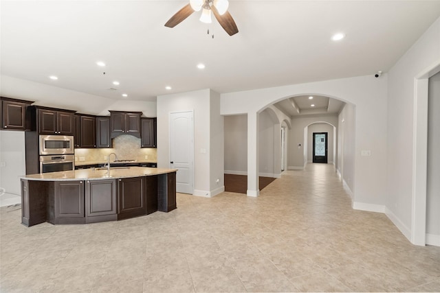 23411 Reynolds Pond Dr, New Caney, TX 77357 - kitchen featuring stainless steel appliances, ceiling fan, backsplash, arched walkways, and a center island with sink