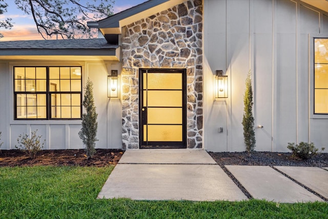 6227 Grovewood Ln, Houston, TX 77008 - exterior entry at dusk featuring stone siding and board and batten siding