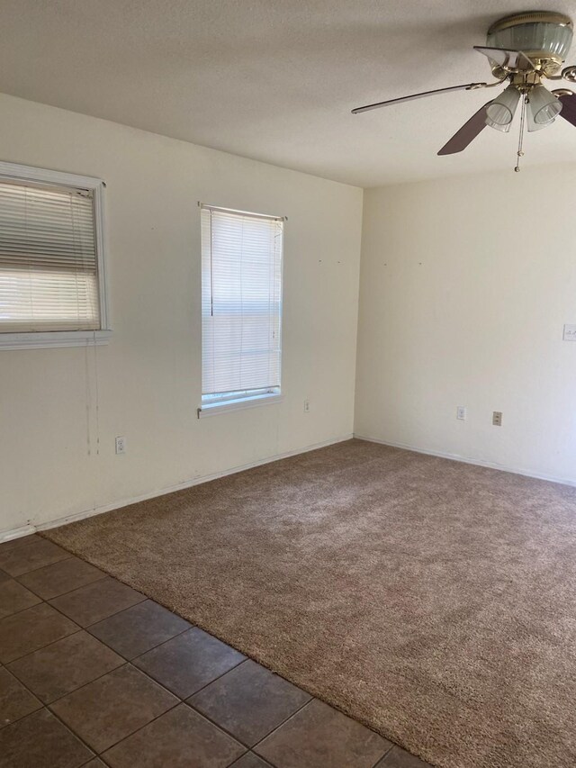 5514 Borden Ave, Galveston, TX 77551 - empty room with ceiling fan, dark carpet, and dark tile patterned flooring