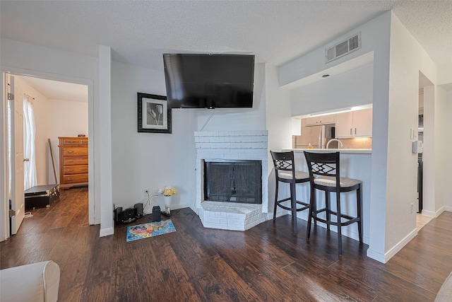 1505 Ward Rd Unit 118, Baytown, TX 77520 - living area featuring wood finished floors, a brick fireplace, and a textured ceiling