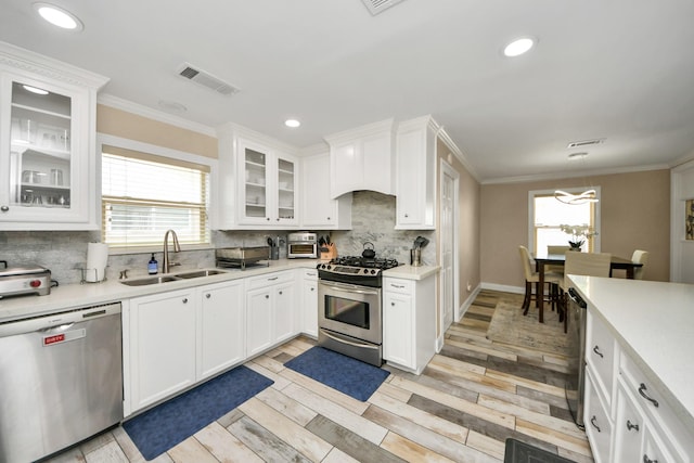 5422 Jason St, Houston, TX 77096 - kitchen featuring appliances with stainless steel finishes, ornamental molding, light countertops, backsplash, and white cabinets