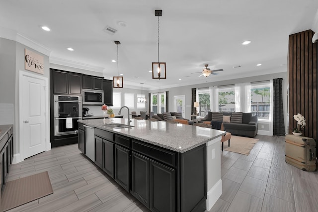 31276 New Forest Park Ln, Spring, TX 77386 - kitchen with appliances with stainless steel finishes, ceiling fan, a kitchen island with sink, light stone countertops, and recessed lighting