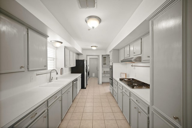 3103 Fairway Dr, Sugar Land, TX 77478 - kitchen with appliances with stainless steel finishes, light countertops, under cabinet range hood, light tile patterned floors, and gray cabinetry
