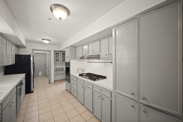 3103 Fairway Dr, Sugar Land, TX 77478 - kitchen featuring stainless steel appliances, under cabinet range hood, light tile patterned floors, gray cabinetry, and light countertops