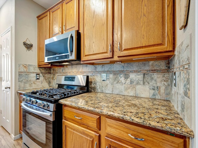 3219 Almond Creek Dr, Houston, TX 77059 - kitchen featuring appliances with stainless steel finishes, tasteful backsplash, light stone counters, and brown cabinets