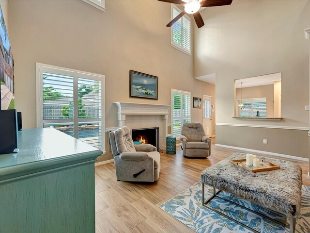 3219 Almond Creek Dr, Houston, TX 77059 - living room featuring a tiled fireplace, ceiling fan, a high ceiling, and light wood-style flooring