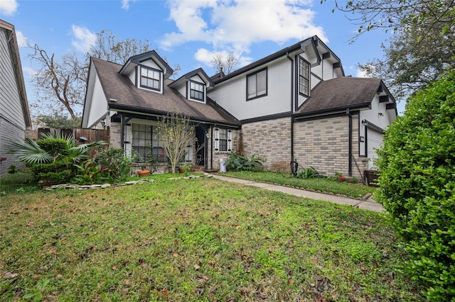 19922 Big Timber Dr, Humble, TX 77346 - tudor home featuring a front yard, an attached garage, brick siding, roof with shingles, and a porch