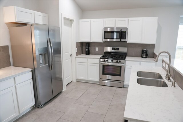 6926 Glenmoor Dr, Rosharon, TX 77583 - kitchen with appliances with stainless steel finishes, decorative backsplash, white cabinets, and light tile patterned floors