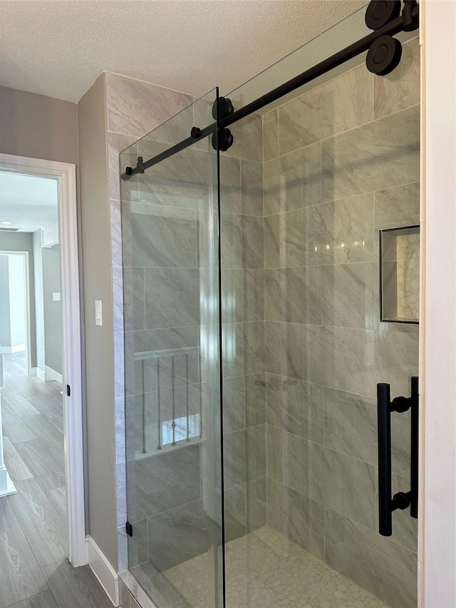 2922 Field Line Dr, Sugar Land, TX 77479 - full bathroom featuring a stall shower, a textured ceiling, and wood finished floors