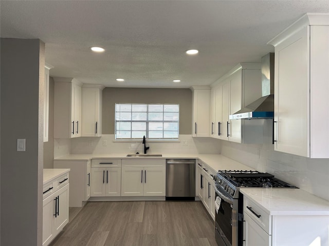 2922 Field Line Dr, Sugar Land, TX 77479 - kitchen with stainless steel appliances, wall chimney range hood, white cabinetry, light wood-type flooring, and recessed lighting