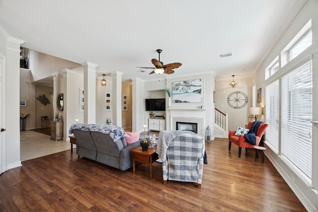 1155 Rustling Wind Ln, League City, TX 77573 - living area featuring wood finished floors, crown molding, a ceiling fan, a fireplace, and decorative columns