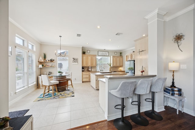 1155 Rustling Wind Ln, League City, TX 77573 - kitchen with light brown cabinets, freestanding refrigerator, crown molding, a kitchen bar, and a peninsula