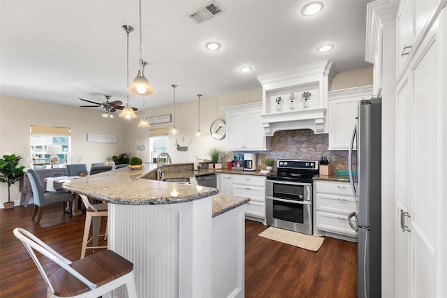 862 Gregory Ln, Port Bolivar, TX 77650 - kitchen with stainless steel appliances, exhaust hood, ceiling fan, a breakfast bar, and dark wood-style floors