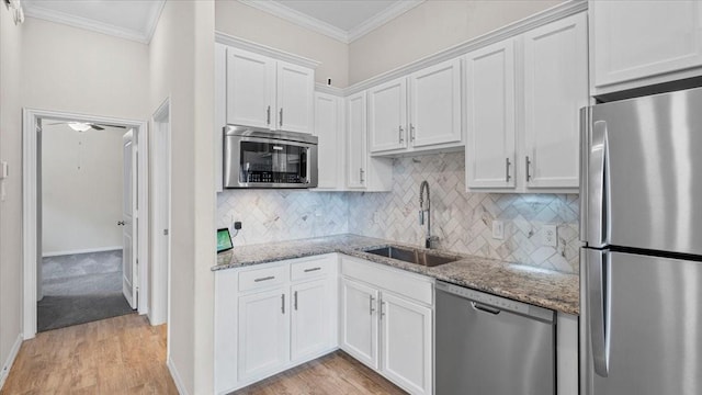 4542 Shallow Ember Dr, Spring, TX 77386 - kitchen featuring appliances with stainless steel finishes, white cabinetry, light wood finished floors, light stone counters, and crown molding
