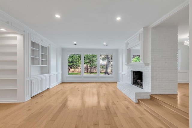 13631 Balmore Cir, Houston, TX 77069 - unfurnished living room with light wood-style flooring, a fireplace, crown molding, built in shelves, and recessed lighting