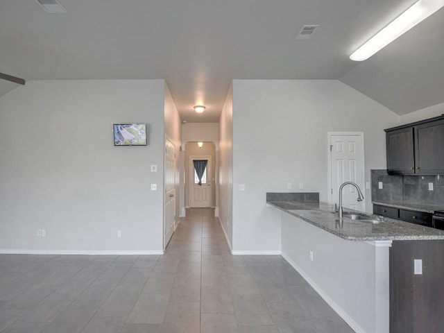 3635 W L Breeding Dr, Corpus Christi, TX 78414 - kitchen featuring vaulted ceiling, light stone counters, a peninsula, tasteful backsplash, and dark brown cabinets