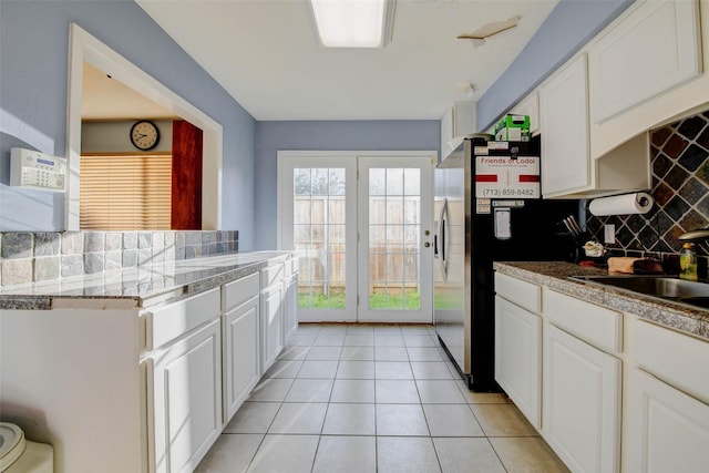 5651 Pine St, Houston, TX 77081 - kitchen with tasteful backsplash, white cabinetry, light tile patterned floors, freestanding refrigerator, and light countertops