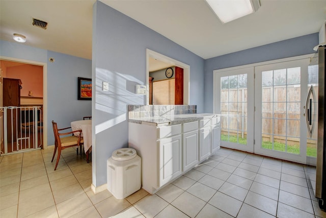 5651 Pine St, Houston, TX 77081 - kitchen with light tile patterned floors, white cabinetry, light countertops, and freestanding refrigerator