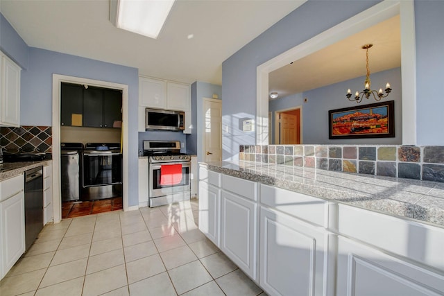 5651 Pine St, Houston, TX 77081 - kitchen with stainless steel appliances, white cabinets, tasteful backsplash, a chandelier, and light tile patterned flooring