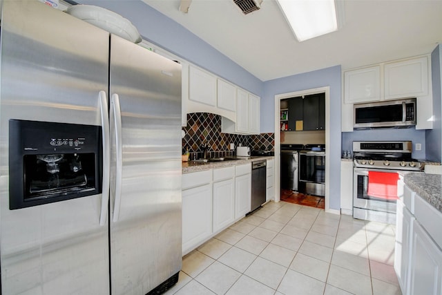 5651 Pine St, Houston, TX 77081 - kitchen featuring stainless steel appliances, white cabinets, light tile patterned flooring, and decorative backsplash