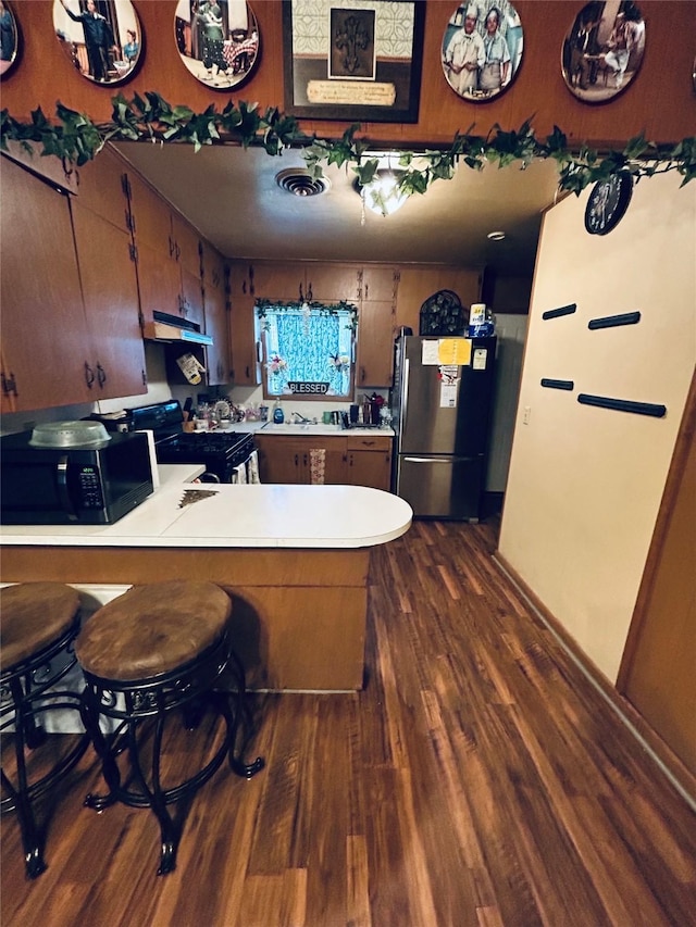 102 Draper St, Columbus, TX 78934 - kitchen featuring black appliances, under cabinet range hood, dark wood-type flooring, light countertops, and a peninsula