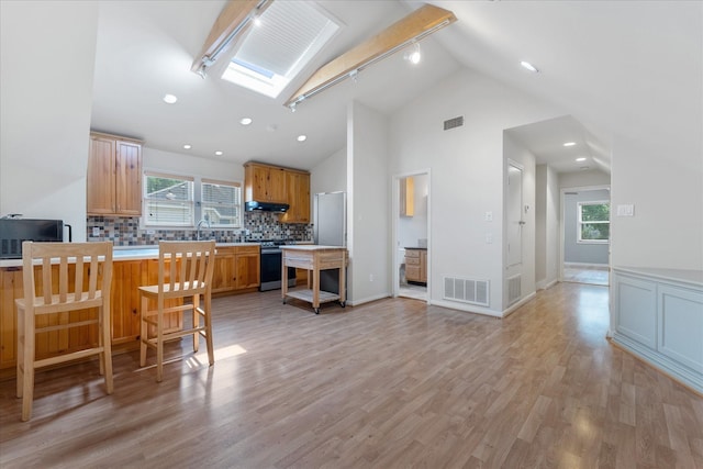 4206 Law St, Houston, TX 77005 - kitchen featuring stainless steel range, under cabinet range hood, decorative backsplash, freestanding refrigerator, and a breakfast bar