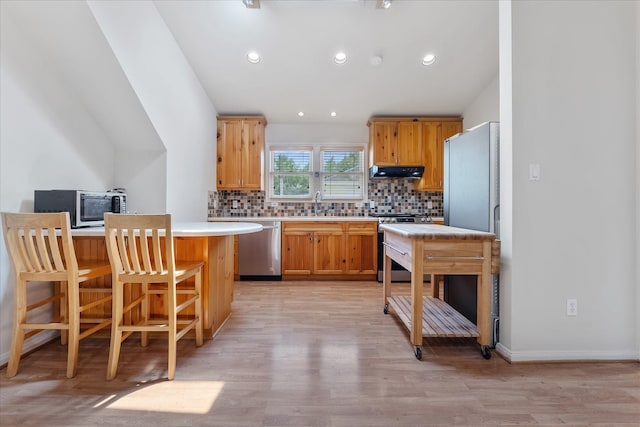 4206 Law St, Houston, TX 77005 - kitchen with stainless steel appliances, under cabinet range hood, backsplash, light countertops, and light wood-style floors