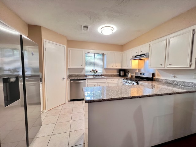 18738 Shannon Glen Ln, Houston, TX 77084 - kitchen featuring appliances with stainless steel finishes, under cabinet range hood, a peninsula, white cabinetry, and dark stone counters