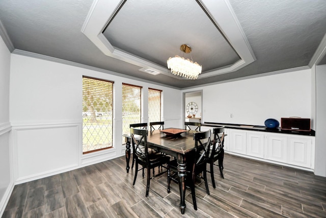 2514 Loganberry Cir, Seabrook, TX 77586 - dining room featuring a tray ceiling, a chandelier, crown molding, dark wood-style flooring, and wainscoting
