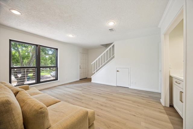 33 Lakewood Ln, Seabrook, TX 77586 - living room featuring ornamental molding, light wood-style flooring, stairway, and a textured ceiling