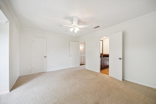 33 Lakewood Ln, Seabrook, TX 77586 - unfurnished bedroom with light carpet, crown molding, ensuite bathroom, a ceiling fan, and a textured ceiling