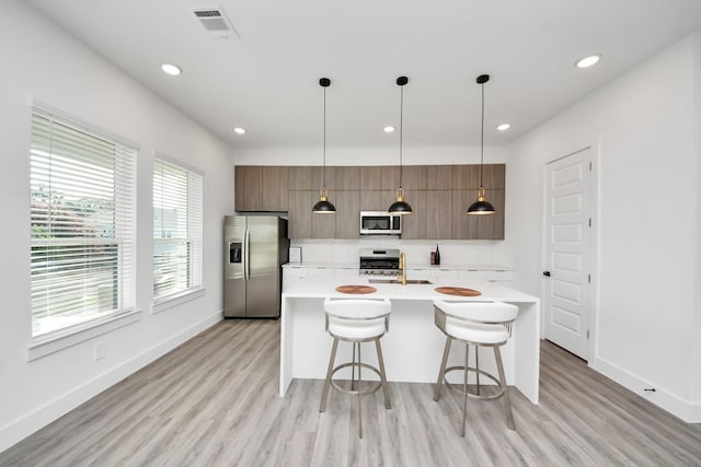 3602 Runnels St, Houston, TX 77003 - kitchen featuring stainless steel appliances, modern cabinets, light countertops, decorative backsplash, and a breakfast bar area