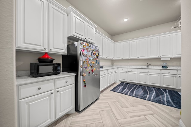 17023 Sweet Bay Ct, Conroe, TX 77385 - kitchen with freestanding refrigerator, black microwave, white cabinets, and recessed lighting