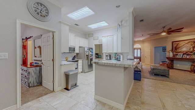 7475 Wooded Creek Dr, Beaumont, TX 77708 - kitchen with appliances with stainless steel finishes, white cabinets, open floor plan, a peninsula, and decorative backsplash