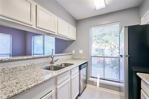 3724 Woodchase Dr, Houston, TX 77042 - kitchen featuring stainless steel appliances, white cabinetry, and light stone counters