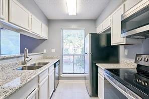 3724 Woodchase Dr, Houston, TX 77042 - kitchen with stainless steel appliances, white cabinets, healthy amount of natural light, and light stone countertops