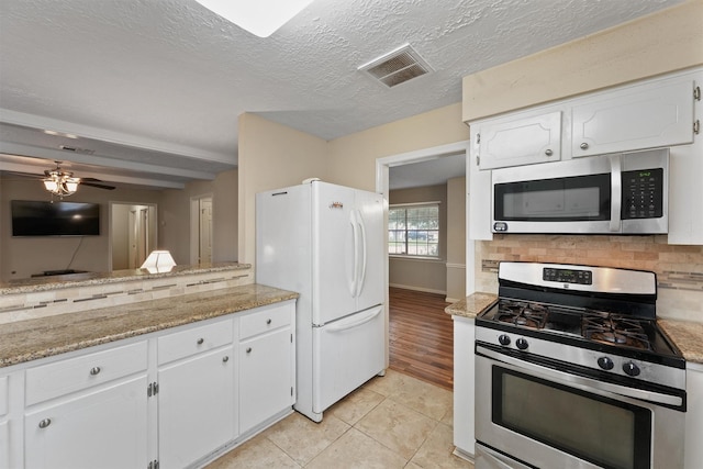 9602 Philmont Dr, Houston, TX 77080 - kitchen featuring stainless steel appliances, tasteful backsplash, white cabinets, light tile patterned floors, and a ceiling fan