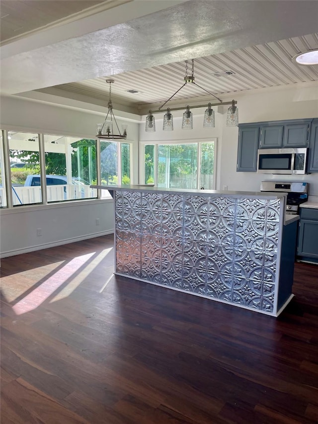717 W Brazos St, Freeport, TX 77541 - kitchen with stainless steel microwave, dark wood finished floors, light countertops, and decorative light fixtures